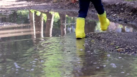 The boy jumps in a puddle . A boy in rubber boots. Happy childhood. Summer Stock Footage 150064132