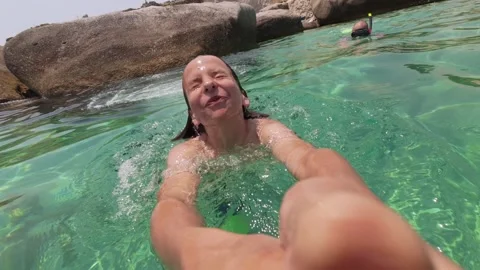 Boy jumps into the sea while holding an action camera, capturing the full dive Stock Footage 313809607