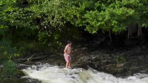 Boy jumps from smallscale waterfall, sideview Stock Footage 166640109