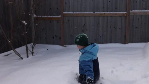 Boy jumps into snow face first in backyard after first snow fall of winter Stock Footage 304235081