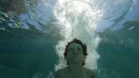 Boy Jumps Into Sunny Pool Stockbeeldmateriaal 129731104