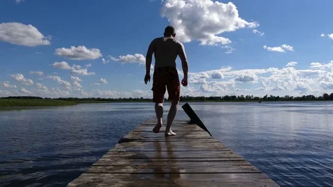 Boy jumps into the water with a pier Stock Footage 78778766