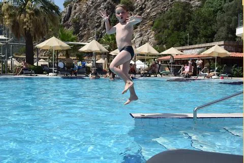 The boy jumps into the water of the pool. Fotos Stock