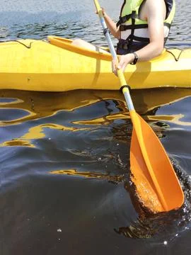 A boy in a kayak in a life jacket pulls out an oar. Side view Stock Photos