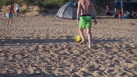 The boy kicking the ball on the sandy be... | Stock Video | Pond5