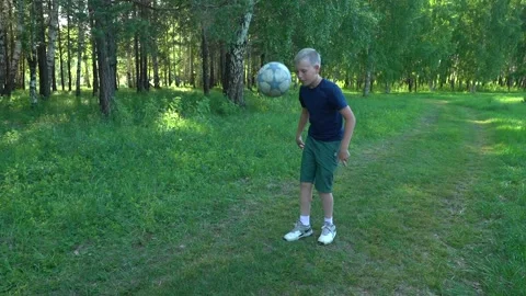 A boy is kicking a ball while practicing in a summer park. Slow motion Stock Footage 166554229