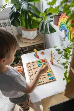 Boy kid assembling flat letters wooden puzzle block cell playing childish Stock Photos