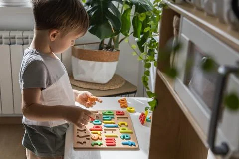 Boy kid assembling flat letters wooden puzzle block cell playing childish Stock Photos