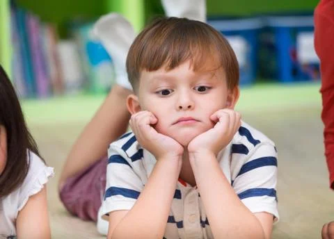 Boy kid lay down on library floor with bored feeling in preschool library,Kin Stock Photos