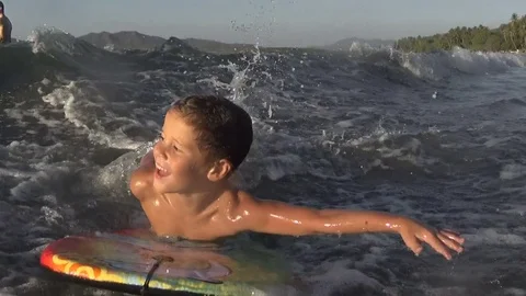Boy / kid surfing swimming - jumping waves Body Board Stock Footage