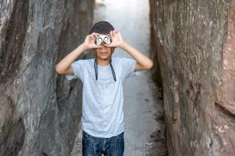 Boy kids holding telescope looking nature on road walking between hills  Stock Photos