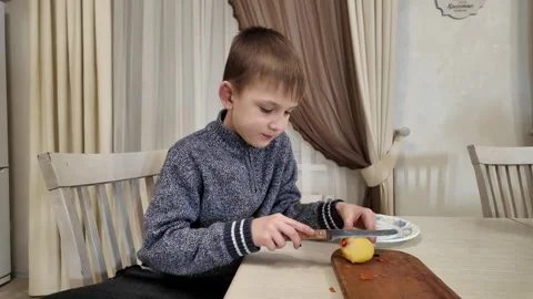Boy in kitchen preparing food, cutting boiled potatoes for salad Stock Footage 303494793