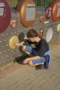 A boy is kneeling down in front of a machine with a red button Stock Photos