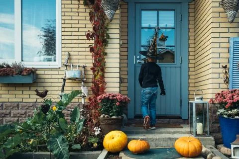 The boy knocking at the house with pumpkins. Stock Photos