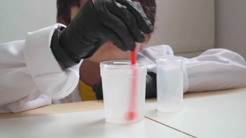 Boy in lab coat and black gloves doing sciences experiment Stock Footage 280684877