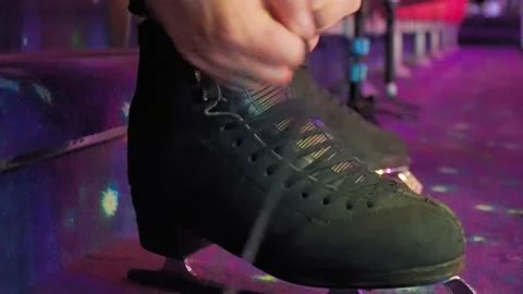 Boy lace up skates to train on ice rink Stock Footage 137455925