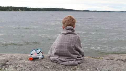 Boy at lake. Cold summer day. Video stock 256106658
