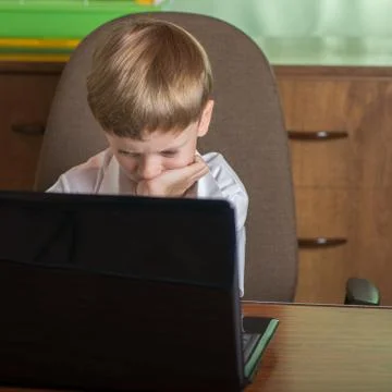 Boy with laptop at table Stock Photos