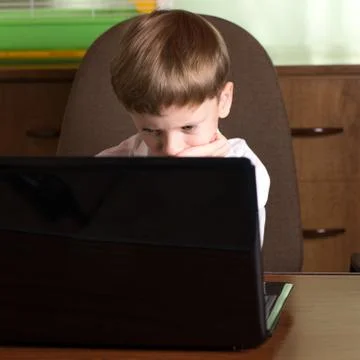 Boy with laptop at table Stock Photos