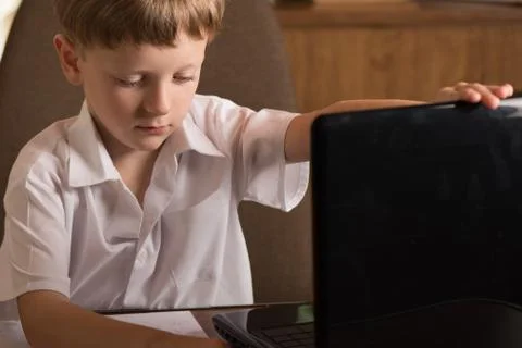 Boy with laptop at table Stock Photos