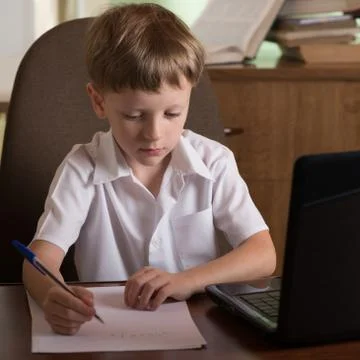 Boy with laptop at table Stock Photos