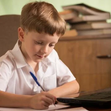 Boy with laptop at table Stock Photos