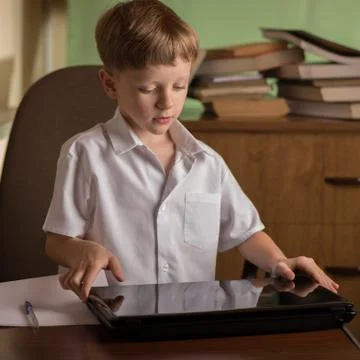 Boy with laptop at table Stock Photos