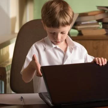 Boy with laptop at table Stock Photos