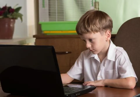 Boy with laptop at table Stock Photos