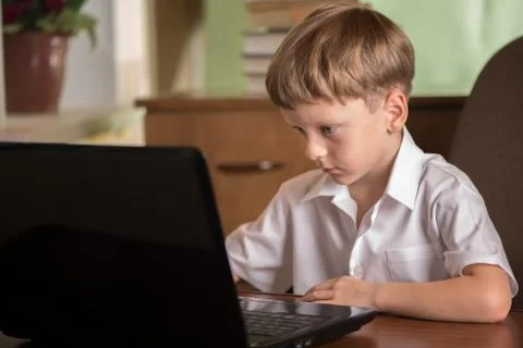 Boy with laptop at table Stock Photos