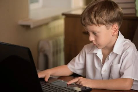 Boy with laptop at table Stock Photos