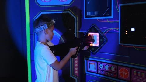 A boy in a laser tag game runs up to recharge and charges his laser weapon. Stock Footage 323362814