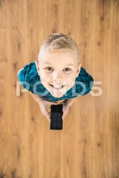 The boy laugh to camera and hold a phone in hands. View from above Stock Photos