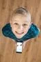 The boy laugh to camera and hold a phone in hands. View from above Photo