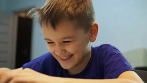 The boy laughs very hard sitting on a chair at the table Stock Footage 144934960