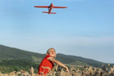 Boy launch model airplane into the sky. Red toy plane against blue sky. Happy 스톡 사진