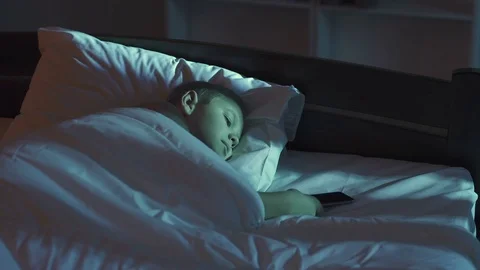 The boy lay on the bed and phone. Evening night time. Real time capture Stock Footage 71965913