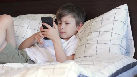 Boy laying in bed and using smartphone Stock Footage 158786250