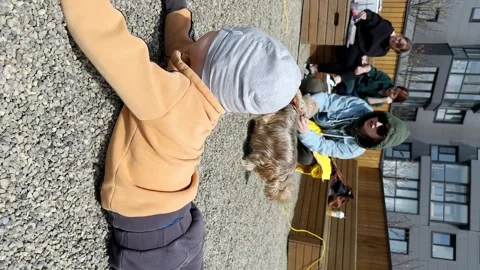 Boy laying on his belly and playing with pebbles on the playground in the yard Stock Footage 263178223