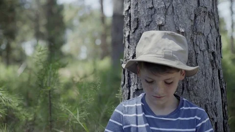 Boy leaning against tree trunk, portrait Stock Footage 75179270