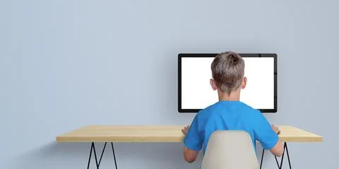 Boy learn to code on desktop computer concept. A boy in a blue shirt with his Foto stock