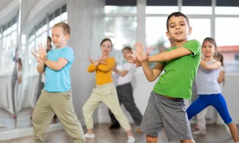 Boy learn to dance modern dances, repeat movement with unrecognizable teacher. Stock Photos