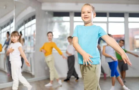 Boy learn to dance modern dances, repeat movement with unrecognizable teacher. Stock Photos