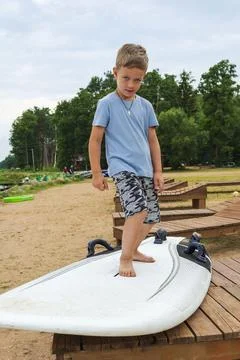 Boy learn to stand on the surf on the beach on the shore of the lake, sea, wa Foto stock