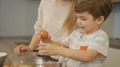Boy learning to crack an egg Stock Footage 100000618