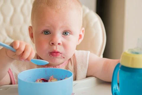 Boy learning to eat. cute messy baby eating vegetables with spoon by yourself in Stock Photos