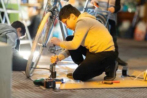 Boy learning to fix bicycle tire with pump 스톡 사진