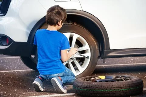 Boy learning how to change tyre using wheel brace Stock Photos