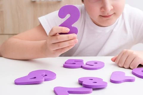 A boy learning math, count exercises at home, holding colorful foam numbers in Stock Photos