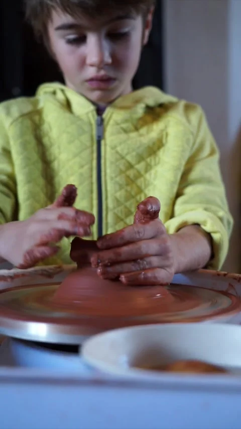 Boy learning to mold clay on the potter's wheel Stock Footage 258592985